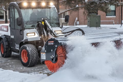 A Toolcat Utility Work Machine Clears Snow With the Angle Broom Attachment