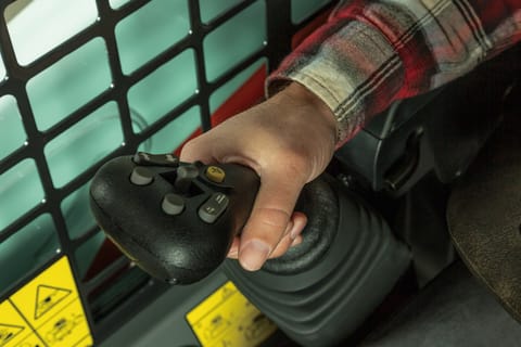 Interior Of The Bobcat S510 Skid-Steer Loader With The Operator’s Hand Resting On The Selectable Joystick Control