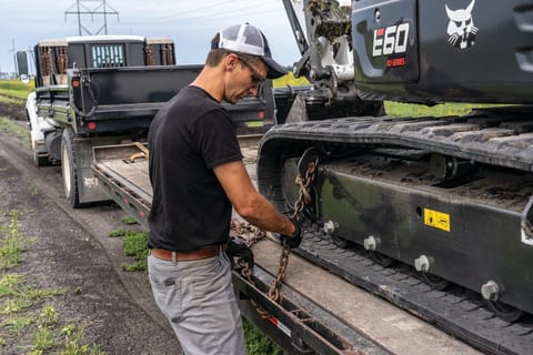 Operator loads an R2-Series E60 compact excavator on a trailer