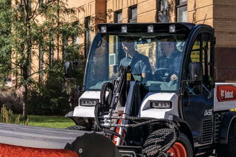 Utility Work Machine Operator Using a Sweeper Attachment