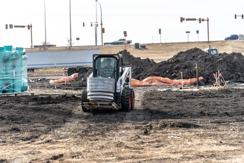 Bobcat S510 Skid-Steer Loader Carrying Heavy Materials Across Crowded Construction Area