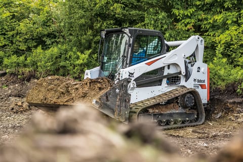  A T770 compact track loader uses a bucket to move dirt and mulch 