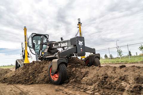 Bobcat compact track loader equipped with a grader attachment leveling soil on a construction site.