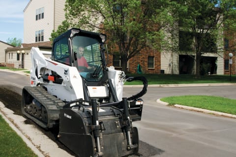 Bobcat planer attachment mounted to a compact track loader cuts an asphalt parking lot