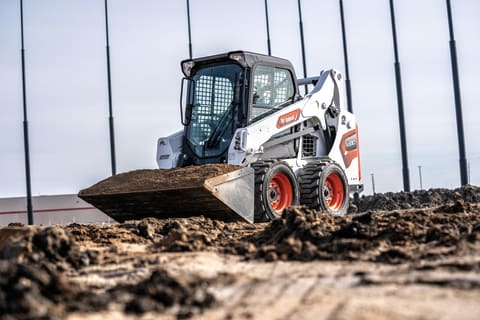 Bobcat S590 Skid-Steer Loader Hauling Dirt Across A Construction Site