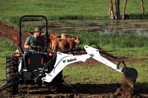 Operator digging with a compact tractor and backhoe tractor implement 