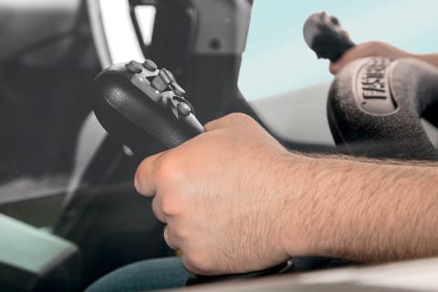 A loader operator uses joystick controls