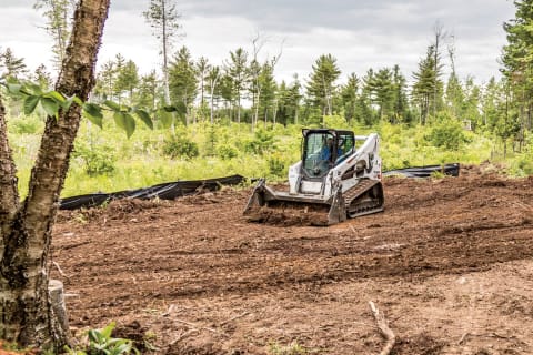 Compact track loader moves dirt with bucket
