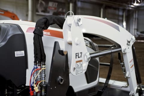 Side view of removing the front-end loader from a Bobcat compact tractor.