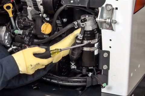 A Bobcat technician demonstrates how to change a fuel filter on a loader.