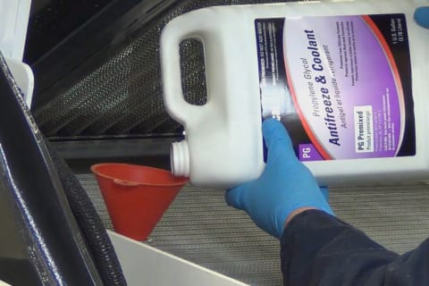 Closeup Of Technician adding Bobcat coolant to an R-series Loader