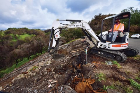 JM Environmental Employee Using Bobcat S650 Compact Excavator With Clamp Attachment To Clean Up Debris