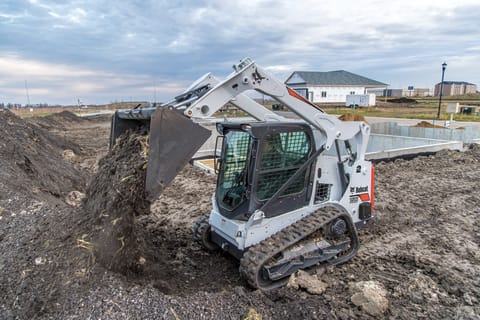 Bobcat T595 compact track loader dumping dirt on construction site