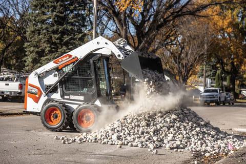 Bobcat S450 Skid-Steer Loader Dumping Landscape Rock Onto Pile