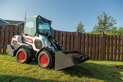 Operator Hauls Dirt On Established Landscape Using Bucket Attachment On Small Articulated Loader
