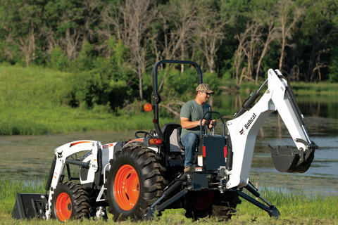 Bobcat compact tractor with front-end loader attachment and backhoe attachment.