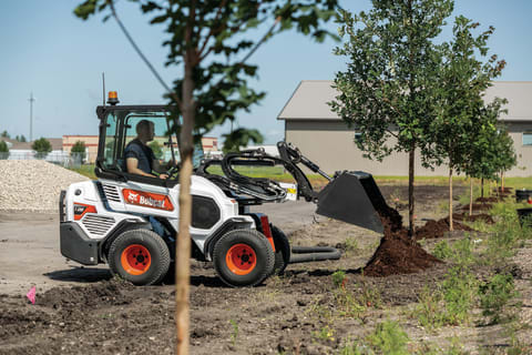 Landscaper Moving Rock With Bobcat Compact Track Loader