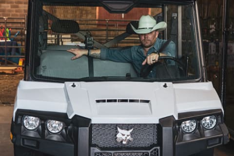 Justin Moore driving a Bobcat utility vehicle