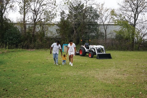 Parents And A Small Child Walking Next To A Bobcat Compact Tractor