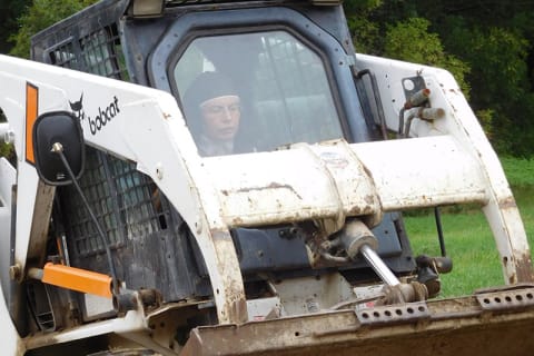 Nun Operating A Bobcat Skid-Steer Loader