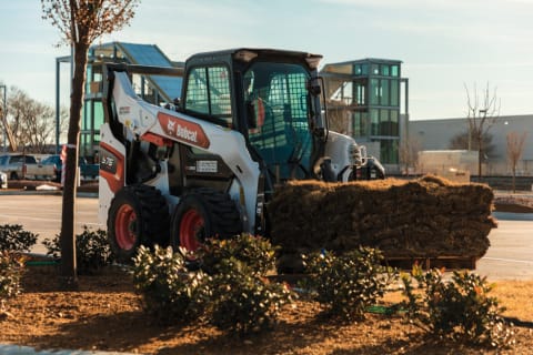 Bobcat S76 Skid-Steer Loader Carrying A Pallet of Sod Using the Pallet Fork Attachment