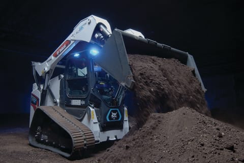 The Bobcat T7X compact track loader drops dirt from its bucket into a pile. 