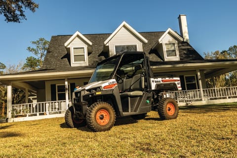 Un vehículo utilitario Bobcat estacionado frente a una casa