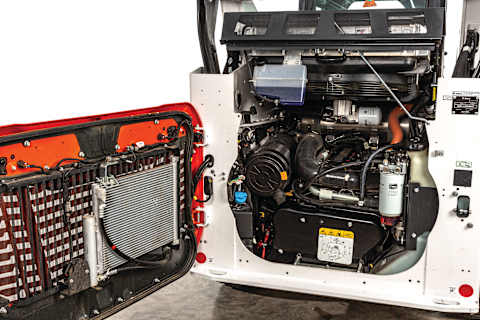 Open rear engine compartment of a Bobcat Compact loader showing easy access to filters, fluids, and key service components for simplified maintenance.