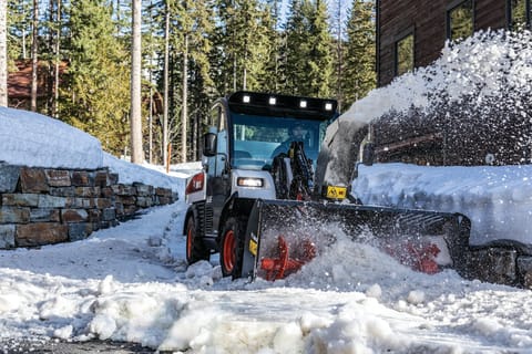 Bobcat UW56 Toolcat Utility Work Machine With Snowblower Attachment Clearing Snow Off Path