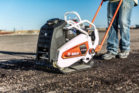 Operator using the Bobcat Forward plate compactor highlighting the water tank and sprinkler system.