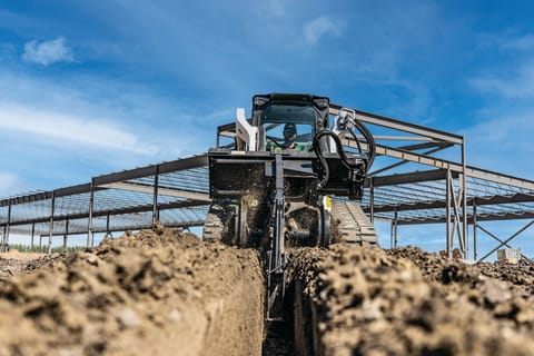 A Bobcat T86 Compact Track Loader Digging a Trench With the Trencher Attachment