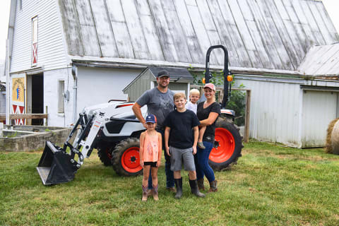 Hawkins family standing in front of Bobcat CT2025 compact tractor with their barn in background