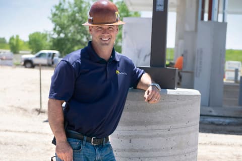 John Christianson, owner of The Caisson Company, posing in hard hat leaning against light pole base