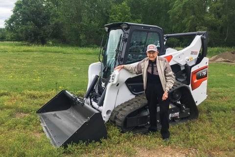 Cy Keller standing next to a Bobcat R-Series T76 compact track loader. 