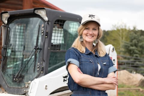 Heidi Bradberry, co-owner of West Wind Stables, stands in front of her Bobcat T450 compact track loader. 