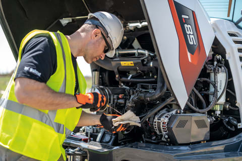 Operator Performs Routine Maintenance To The Bobcat Engine Of a Compact Wheel Loader.