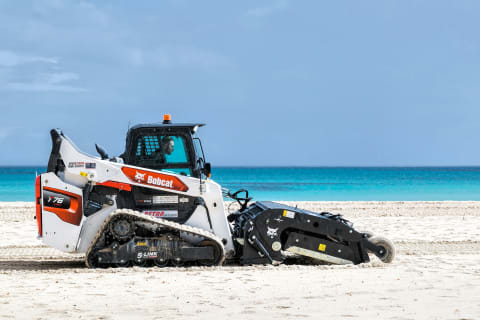 Chargeuse sur chenilles Bobcat avec accessoire nettoyeur de sable sur la plus célèbre des plages siciliennes