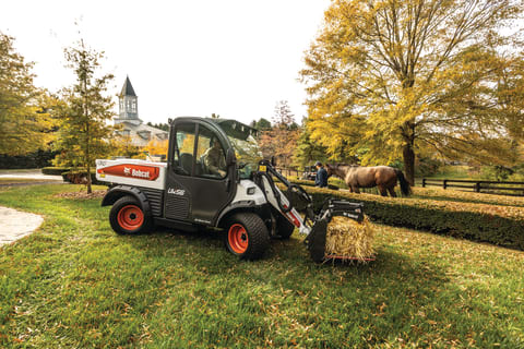 Una máquina de trabajo utilitaria Toolcat levanta un fardo de heno con la pinza utilitaria