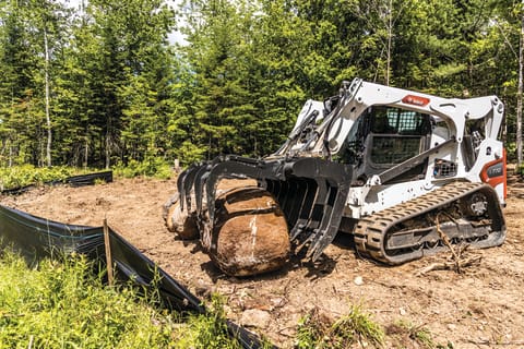 Bobcat loader with roller suspension carrying a large rock