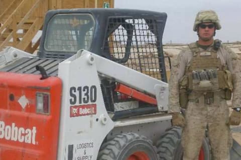 U.S. Marine Sergeant Peter Freundschuh standing next to a Bobcat S130 skid-steer loader in uniform, while deployed at Marjah, Afghanistan in 2010.