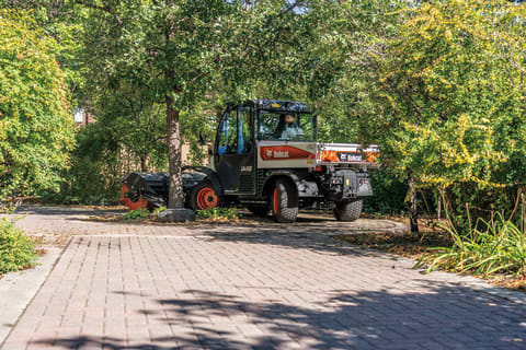 Utility Work Machine Operator Clearing a Brick Path with Angle Broom