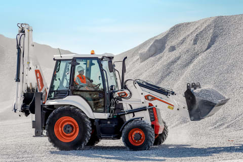 Un opérateur se sert d’une chargeuse-pelleteuse compacte Bobcat pour transporter des matériaux fins dans son godet avant.