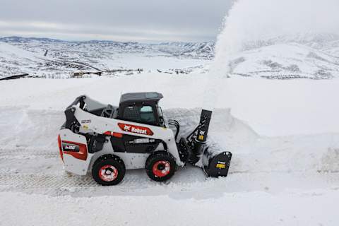 Bobcat S85 skid steer loader creating a path with a snowblower attachment.