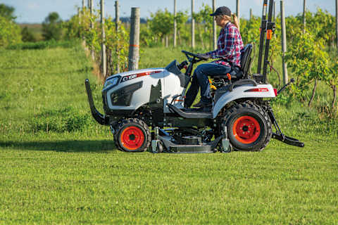 A Female Operator Uses a Bobcat Sub-Compact Tractor Equipped With a Mid-Mount Mower to Cut Grass