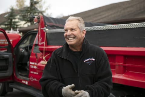 Stan Swogier, owner and founder of Swogier Construction, smiling in front of one of his red company trucks