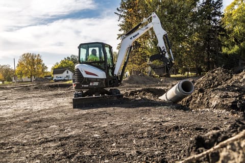 Bobcat E35 compact (mini) excavator moving a concrete pipe into a trench