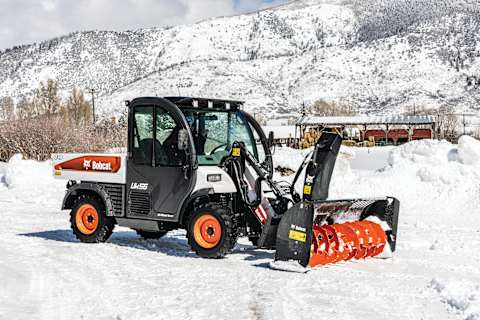 Bobcat Toolcat Utility Work Machine with Snowblower Attachment in Front of Mountains and Barnhouse