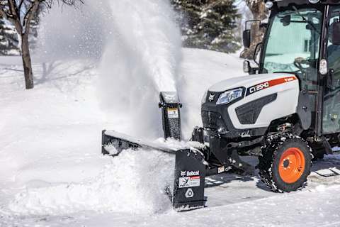 A Bobcat Compact Tractor Blows Snow From a Surface With the Front-Mount Snowblower Attachment