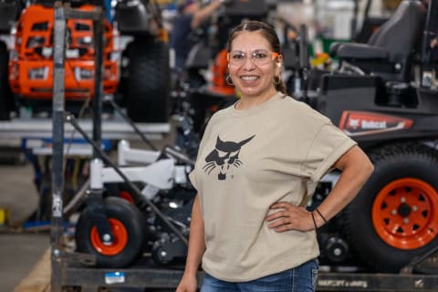 A Bobcat Employee Stands in Front of a Bobcat Mower on the Production Line