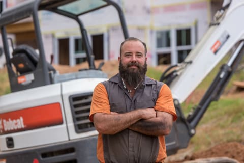 Chonzie McMahan, owner of Chonzie, Inc. in North Carolina stands in front of his Bobcat excavator